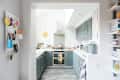 Modern kitchen with gray cabinets, stainless steel appliances, and colorful decor on white countertops.