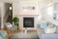Living room with a gray sofa, blue armchair, geometric wall art, fish print, and a fireplace with patterned tiles.