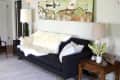 Black sofa with white fur throw, wooden side table, lamps, and abstract wall art in a living room.
