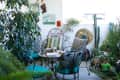 Cozy patio with wrought iron chairs, teal cushions, potted plants, and decorative wall art.