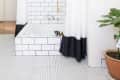 A fully tiled bathroom designed with black-and-white shower curtains