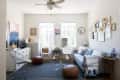 Living room with gray sofa, gallery wall, glass coffee table, poufs, and eclectic decor.