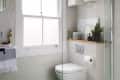 A bathroom with a glass shower door and green floor tiles with a geometric pattern.
