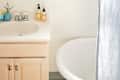 Bathroom with a round tub, light wood vanity, blue shower curtain, and a small mirror on the wall.