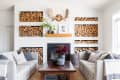 Cozy living room with stacked firewood, white sofas, a wooden coffee table, and a fireplace adorned with moose antlers.