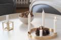 Candles in gold holders and a bowl of walnuts on a white table.
