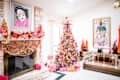 Festive living room with a decorated Christmas tree, colorful garlands on the fireplace, and wrapped gifts.