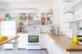 Modern kitchen with white cabinets, wooden countertops, open shelves, and stainless steel appliances.
