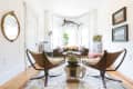 Bright living room with leather chairs, a round table, a sofa, a marlin wall mount, and framed paintings.