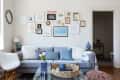 Living room with gray sofa, blue and white cushions, gallery wall, and decorative items on a glass coffee table.
