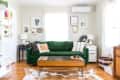 Living room with green sofa, patterned cushions, wooden coffee table, and wall art. White shelves and basket with books.