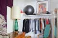 Vintage-style closet with wooden dresser, green chair, clothes rack, framed poster, and exercise ball.