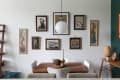 Dining room with a wooden table, white chairs, and eclectic framed art on the wall.
