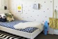 Kids' room with surfboard wall decor, polka dot wall, blue skateboard, zigzag rug, and bed with geometric bedding.