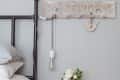 Bedside table with flowers in a jar, a book, and a candle, next to a bed with a metal frame and a hanging light bulb.