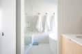 Modern bathroom with glass shower, white towels on hooks, and a wooden vanity.