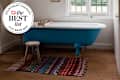 2025 best list seal in corner of image of Free standing Clyde bath from Drummonds in cottage bedroom with Moroccan rug and wooden milking stool