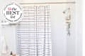 White shower with striped black and white curtain and gold shower caddy. Seal in upper left corner reads "Apartment Therapy the Best List 2023 Shower Organizers"