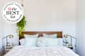 Image of bed with lots of pillows, white shiplap wall, hanging plant. Seal in upper left corner reads "Apartment Therapy The Best List 2024 Silk Pillowcases"