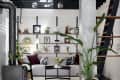 Modern living room with gray sofa, black coffee table, wall shelves, plants, and a wood-burning stove.