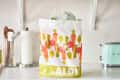 Aldi shopping bag with colorful vegetable design on a kitchen counter next to a mint green toaster.