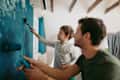 Father and son working together on repainting a wall in their living room
