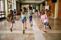 Back view of elementary students running in the school hallway.
