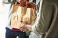 Woman holding paper bag with take out food, home delivery, food order, takeaway
