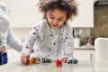 Happy smiling toddler girl playing with toy cars and animal figures in the kitchen