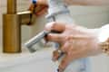 Hands of woman filling water bottle in kitchen sink