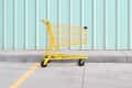 Yellow Shopping Cart On Footpath Against Wall