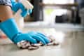 Someone cleaning the floor with a cloth wearing blue rubber gloves