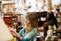 Woman browsing items in a vintage shop, surrounded by eclectic decor and furniture.