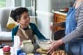 Grandmother making cupcakes with young boy at table in kitchen, learning, togetherness, domestic life.