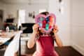 Young girl standing inside with rainbow heart in hands