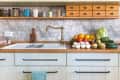 Stack of edible mushrooms, vegetables and fruits (tomatos, avocado, zucchini, oranges, apples, grapefruits, kohlrabi, chinese cabbage, savoy cabbage, cucumbers, radicchio) on countertop in modern rustic kitchen.
