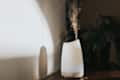 A simple white oil diffuser spritzing a light mist of water and aromatherapy blended oils into the air.