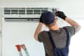 technician inspecting/fixing a central air conditioning unit