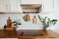 Kitchen brass utensils, chef accessories. Hanging kitchen with white tiles wall and wood tabletop.Green plant on kitchen background