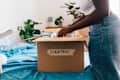 Woman packing donation box on bed at home