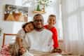 Handsome young man in glasses is posing with his two cheerful kids in the bed