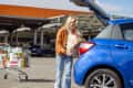 Young woman smiling while putting groceries in the trunk of her car