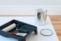 Paint supplies on a hardwood floor, including a roller, brush, tray, and open silver paint can.