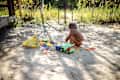 Nature's Playground: Toddler Boy Immerses in Sand Play by the Forest House