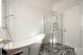 This modern bathroom features a stunning freestanding bathtub, an elegant glass shower, and stylish patterned flooring, perfect for lovers of contemporary interiors and a luxurious atmosphere