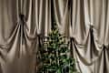 Decorated Christmas tree against Theatrical silver velvet curtain.