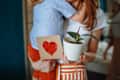 Toddler gives his mom a heart-shaped card and a potted ficus plant for Mother's Day