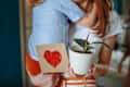 Toddler gives his mom a heart-shaped card and a potted ficus plant for Mother's Day