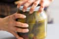 Someone opening jar of pickled cucumbers