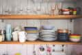 Crockery and drinking glasses on shelves in kitchen at home
